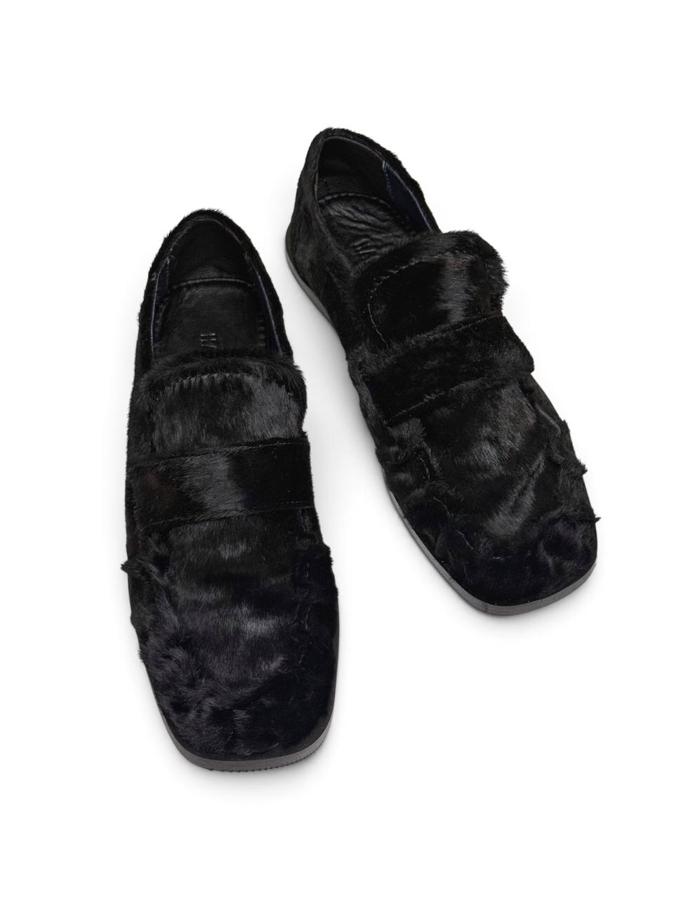 Top view of black loafers highlighting the broad strap and rounded-square toe.