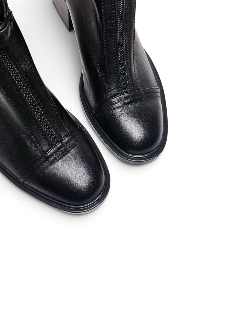 Close-up of rounded toes and stitching on black leather boots