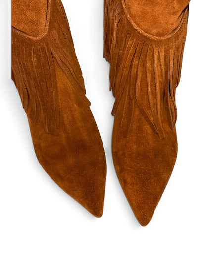 Close-up of pointed brown suede boots with long fringe
