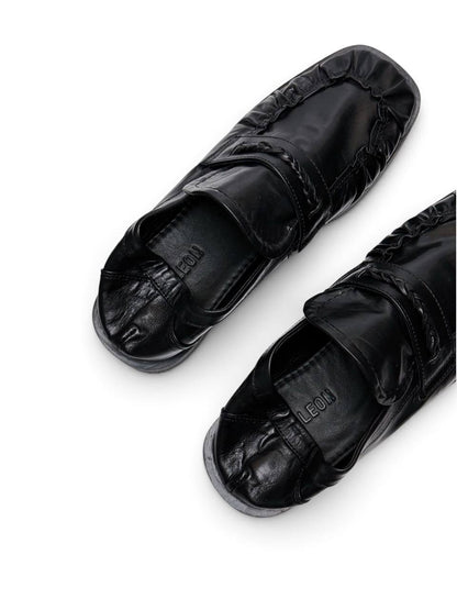 Black leather loafers viewed from above with branded insole and ruched toe
