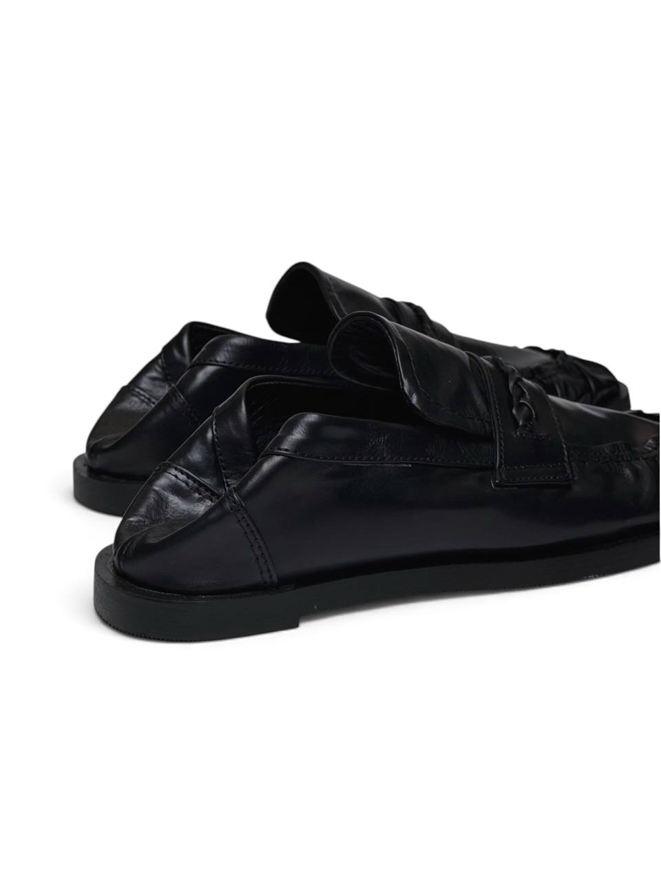 Black leather loafers in side profile with a low heel and ruched toe