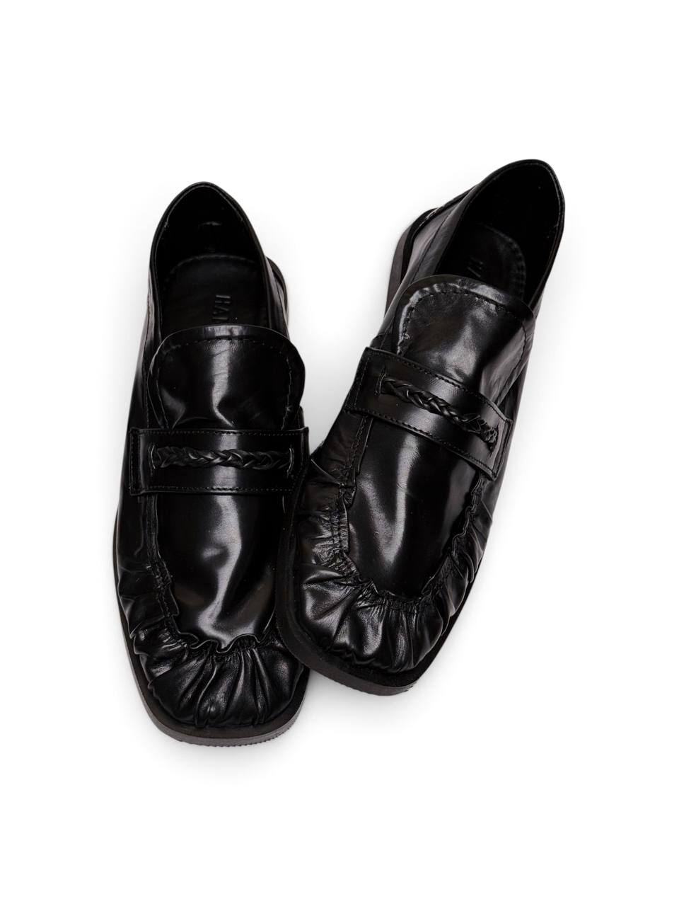 Black leather loafers viewed from above, showing braided straps