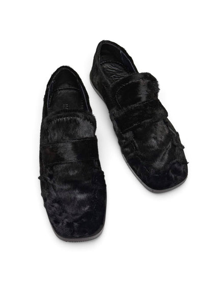 Top view of black loafers highlighting the broad strap and rounded-square toe.