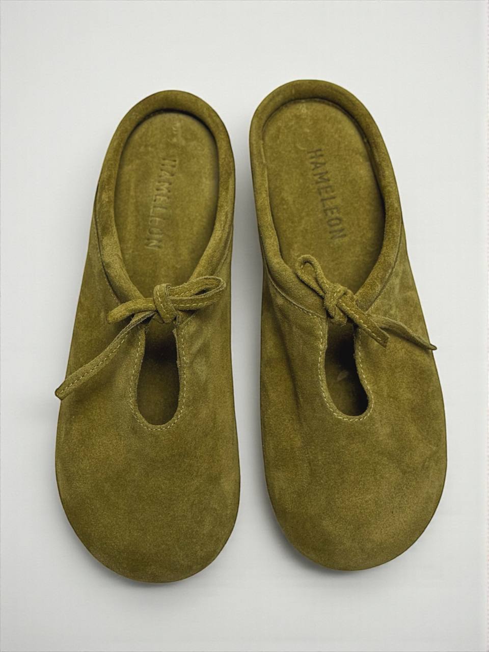 Top view of HAMELEON Mules Lulu Crocus in natural olive suede, showcasing the rounded shape, suede footbed, and artisan craftsmanship