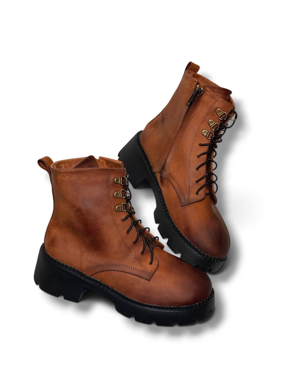 Handmade leather boots featuring metal hooks and dark laces.