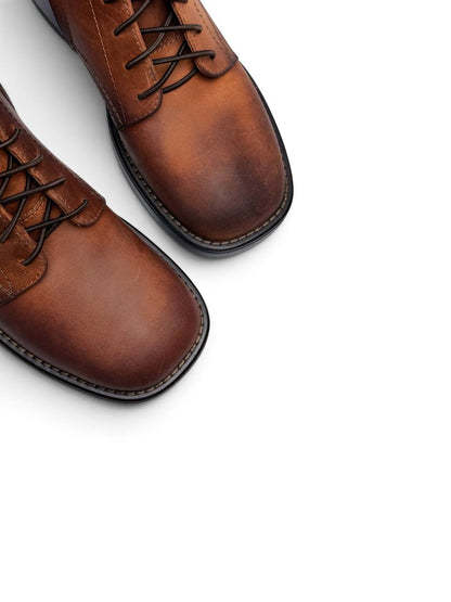 Rounded toes and dark trim on brown leather lace-up boots